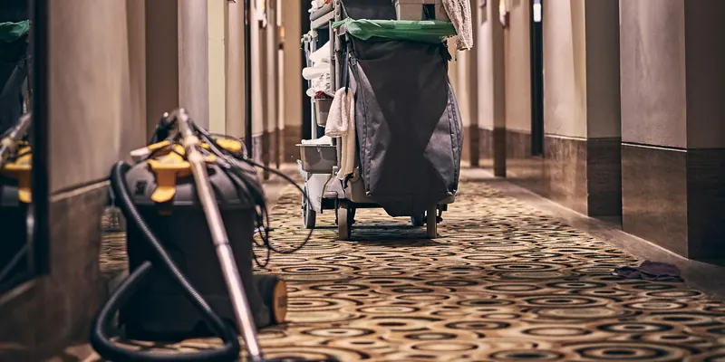 Housekeeping-Wagen und Staubsauger in einem langen Hotelflur