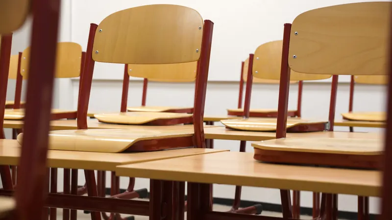 Stühle stehen nach dem Unterricht hochgestellt auf den Tischen eines Klassenzimmers